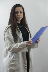 Portrait of young woman standing against wall