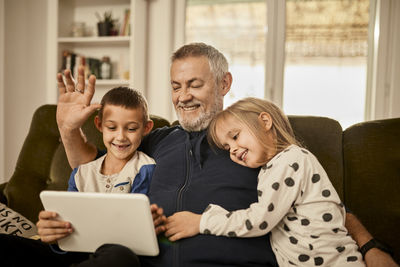 Grandchildren using tablet pc with grandfather at home