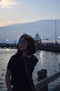 Portrait of young woman standing against sky