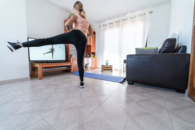 Young woman doing fitness workout at home during isolation quarantine - focus on right foot
