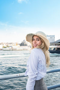 Portrait of smiling young woman standing against sea