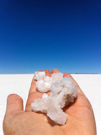 Close-up of hand holding rock against the sky