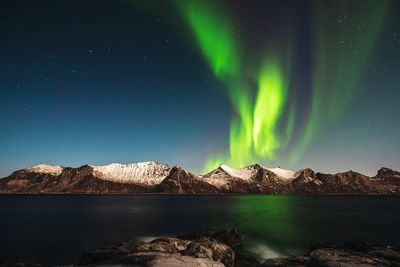 Scenic view of sea and snowcapped mountains against aurora borealis at night