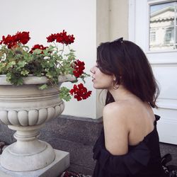 Portrait of woman standing by red flowering plants