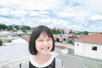 Portrait of smiling young woman against buildings