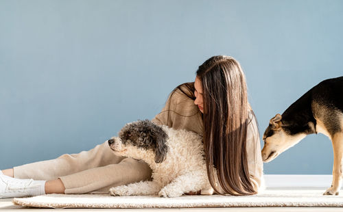 Beautiful brunette woman with playful mixed breed dog, embracing and having fun at home