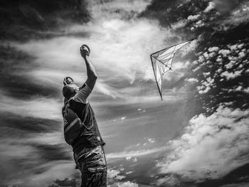 Low angle view of man holding umbrella against sky