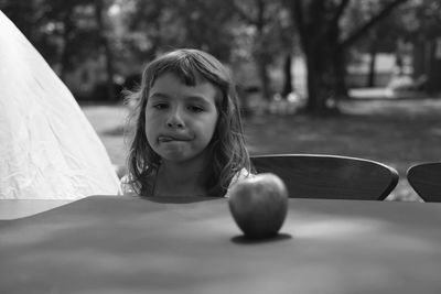 Girl looking at apple on table 