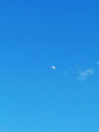 Low angle view of moon against clear blue sky