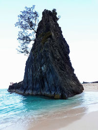 Rock formation in sea against clear sky