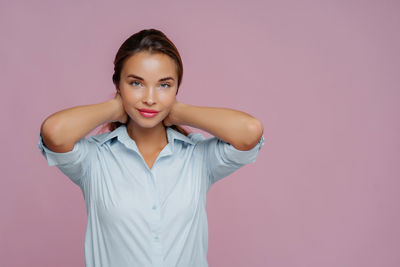 Portrait of young woman standing against white background