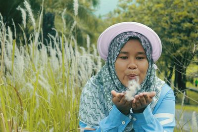 Young woman blowing flowers at park