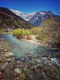 Scenic view of river amidst mountains against clear blue sky