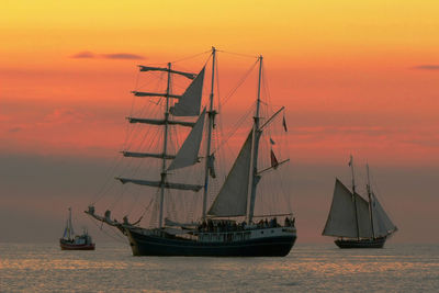 Silhouette of boat sailing in sea at sunset