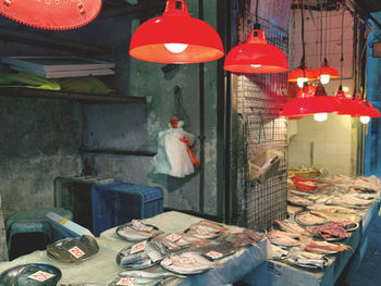 Various seafood for sale under red lamp at a market stall