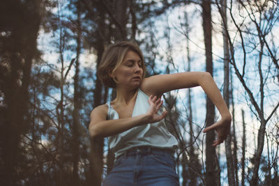 Woman standing by tree in forest