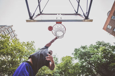 Low angle view of young man playing basketball