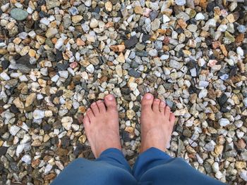 Low section of man standing on pebbles