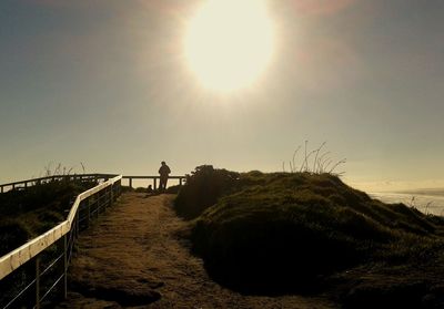 Man standing on beach against clear sky during sunset