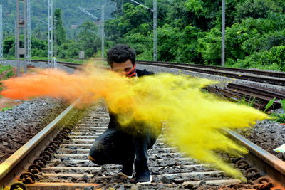 Man crouching with powder paint splattering over railroad track