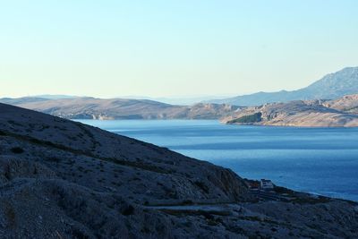 Scenic view of sea and mountains against clear sky