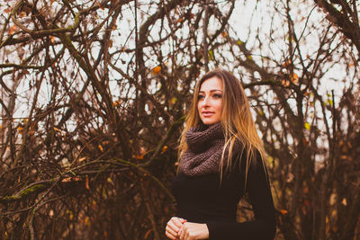 Portrait of young woman standing by tree