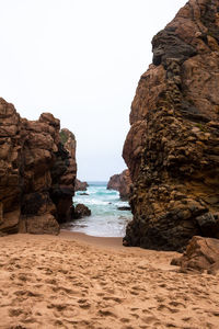 Rock formations on beach against clear sky