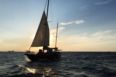 Sailboat sailing on sea against sky during sunset