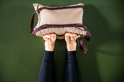 Low section of person holding pillow against green background