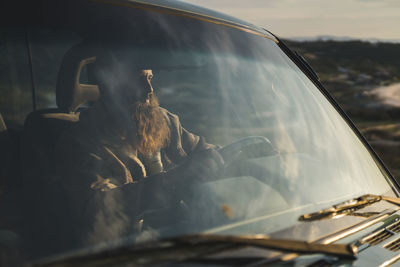 Young man driving car during sunset