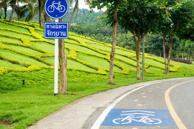 Signboard and trees by road