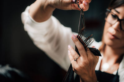 Midsection of hairdresser cutting woman hair in salon