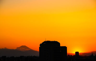 Silhouette buildings against orange sky