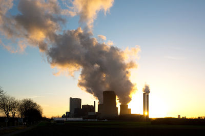 Smoke emitting from factory against sky