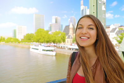 Portrait of smiling young woman against water