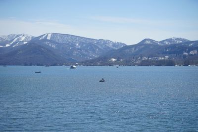 Scenic view of sea by mountains against sky