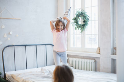 Portrait of woman with arms raised on bed at home