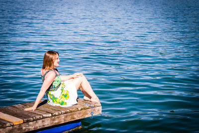 Woman sitting on pier over lake