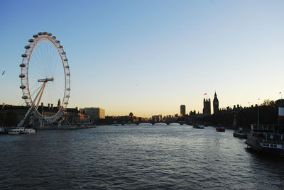 Ferris wheel in city against sky during sunset