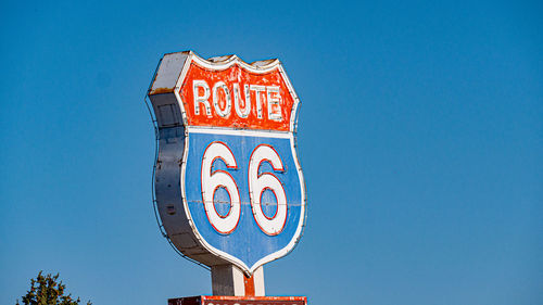Low angle view of road sign against blue sky