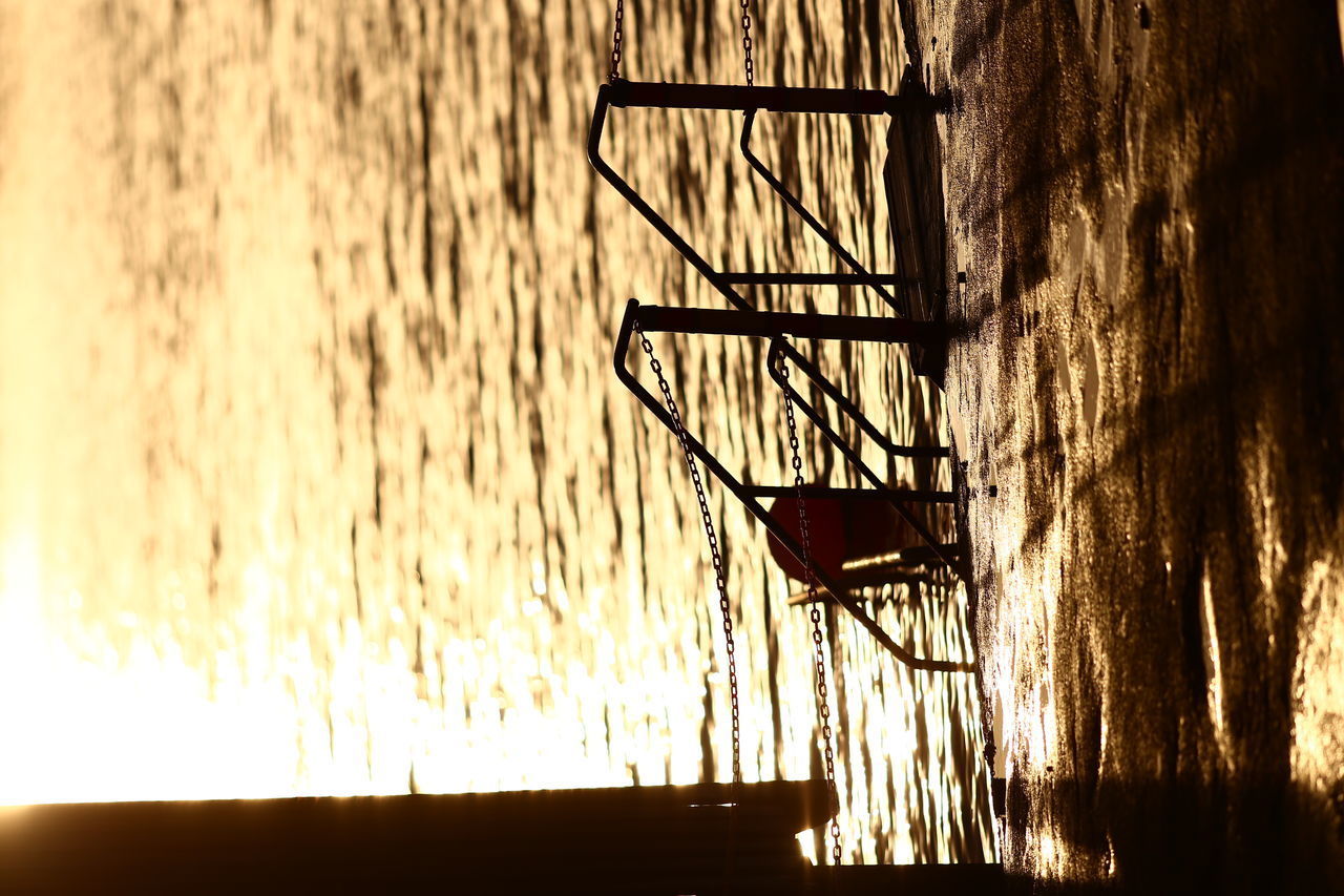 SILHOUETTE OF LADDER AGAINST WALL AT LAKE