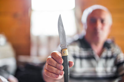 Mature man holding knife at home