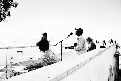 Rear view of people sitting on boat against clear sky