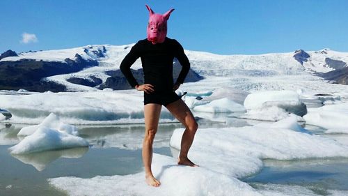 Man wearing pig mask while standing on frozen lake