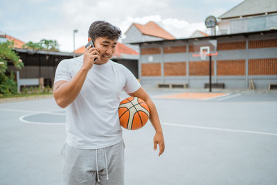 Man talking on mobile phone on basketball court