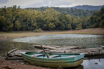Boats moored by lake against trees