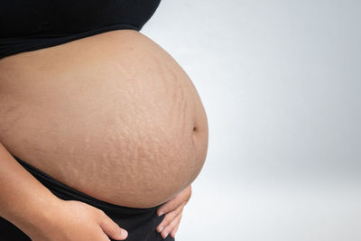 Midsection of woman touching face against white background