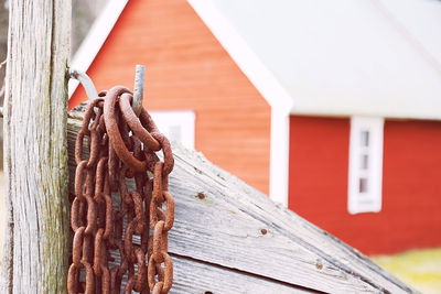 Close-up of rusty metal chains in front of fishing environments and against red wooden building