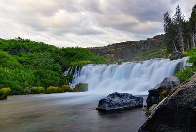 Scenic view of waterfall against sky