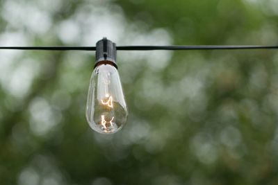 Low angle view of illuminated light bulb hanging outdoors